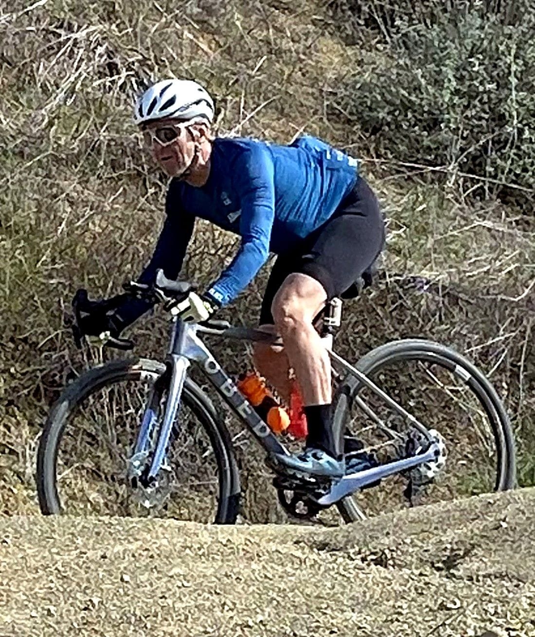 Robert McCray of Fondo Coffee riding a gravel bike on a dirt trail.