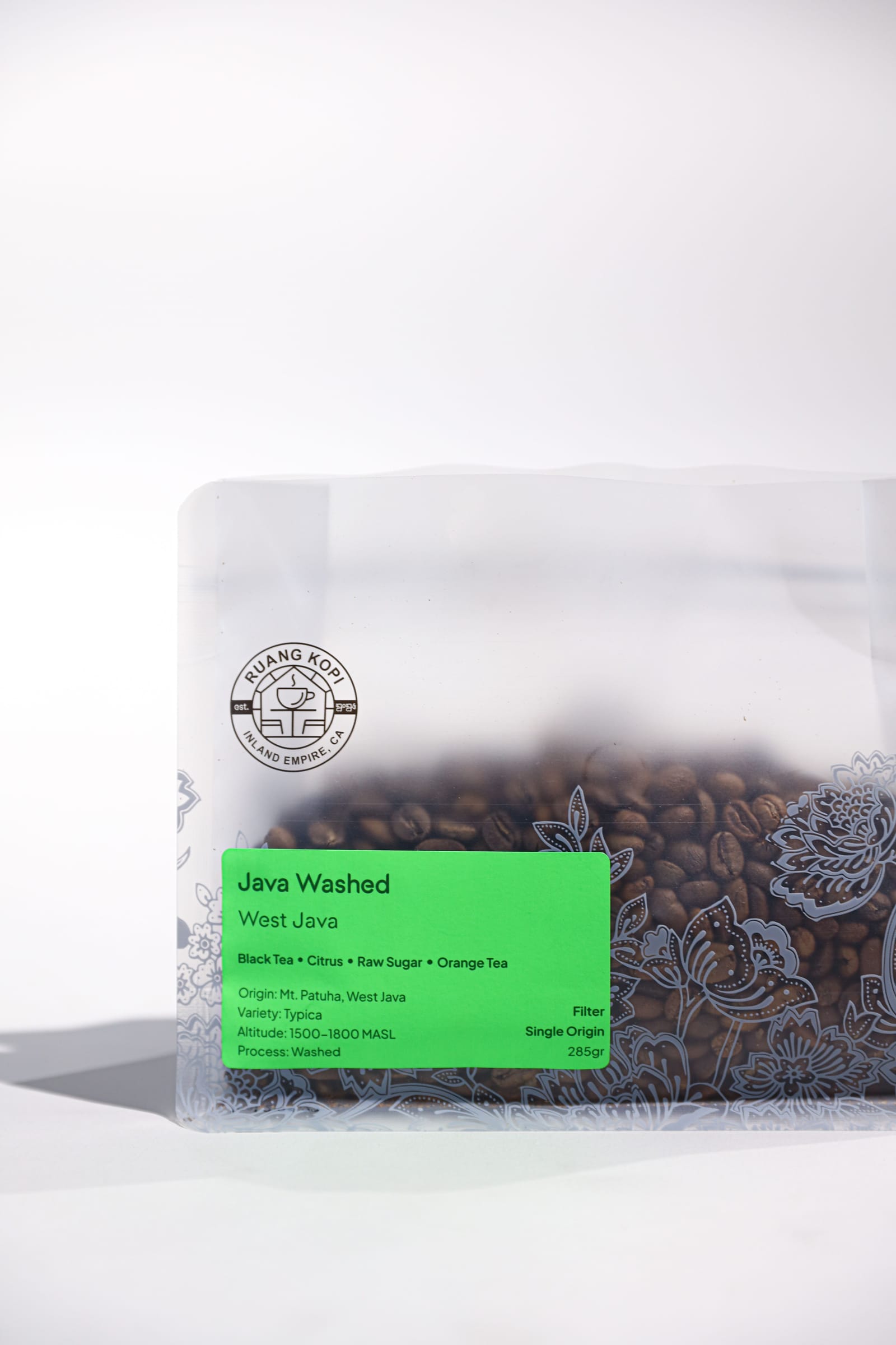 A bag of Ruang Kopi West Java washed coffee, green label reading black tea, citrus and raw sugar.